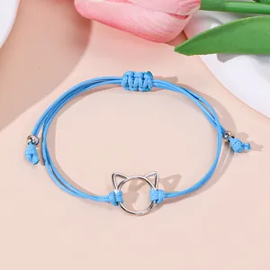 Hemelsblauwe gevlochten kattenarmband met zilveren kattenkop op decoratieve ondergrond