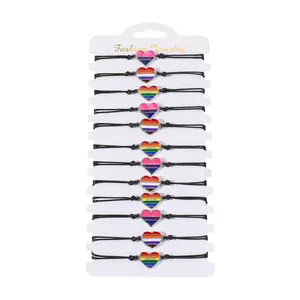 Set of 12 handmade woven heart bracelets with rainbow enamel charms on a display card