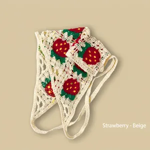 Détail macro du bandana beige tricoté à la main avec motifs de fraises au crochet
