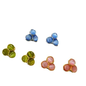 Three pairs of floral cat-eye stone stud earrings in blue, green, and pink colors