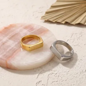 Minimalist stainless steel and 18k gold plated signet rings for men displayed on marble.