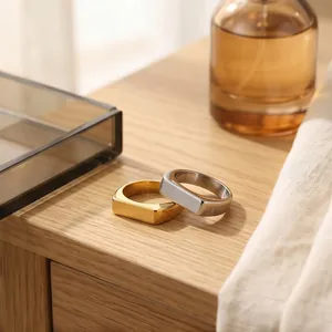 Detailed macro view of minimalist gold and silver signet rings on a wooden surface