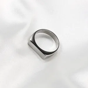 Minimalist silver stainless steel signet ring for men displayed on white silk fabric