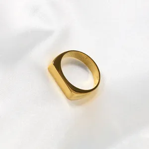 Minimalist 18k gold plated titanium steel signet ring for men on white satin fabric