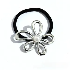 Close-up of a silver hollow flower hair tie with a white pearl on a black elastic band