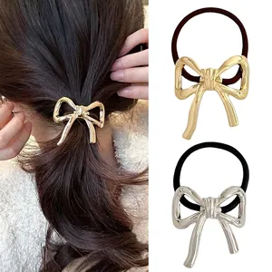 Detail view of metallic bow hair tie with high-elastic band and polished gold finish