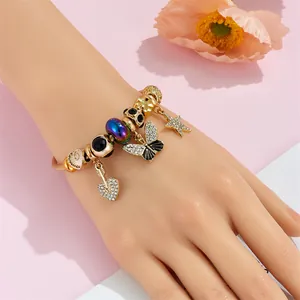Close-up of a gold charm bracelet with crystal stars, butterflies and glass beads on a wrist