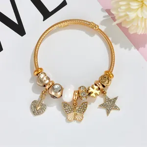 Detail of a gold coil bracelet featuring rhinestone heart, star, and butterfly charms