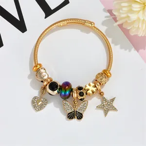 Golden twisted wire bangle with heart, butterfly, and star charms in bohemian style