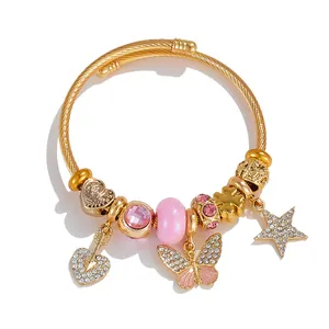 Detail of gold spiral bangle with pink crystal charms and star butterfly pendants