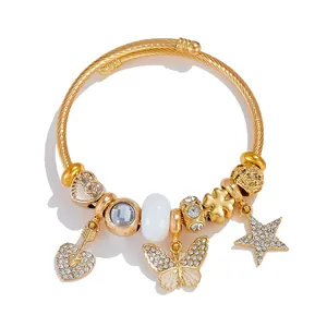 Detail of a gold-tone cable bracelet with crystal heart and butterfly charms