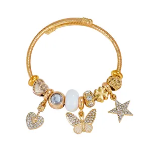 Gold-plated cable bracelet with sparkling heart, star, and butterfly charms on white background