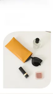 Macro detail of bright orange PU leather sunglasses pouch with squeeze closure mechanism