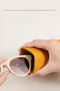 Detail showing hand squeezing the bright yellow leather sunglasses pouch with metal closure
