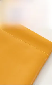 Detailed close-up showing the fine texture and neat stitching of the yellow leather pouch