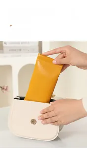 Yellow PU leather sunglass pouch being placed in a white saddle bag for portable storage