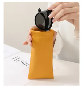 Hand holding ginger yellow leather sunglasses pouch showing its soft PU material texture
