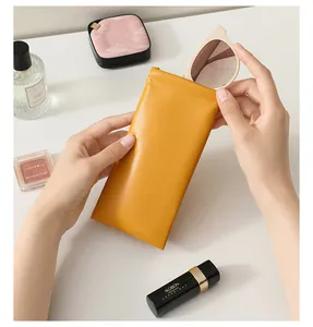 Close-up of hand-held yellow PU leather sunglasses pouch with automatic squeeze closure