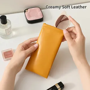 Yellow leather squeeze top sunglasses pouch with soft texture on a white aesthetic desk