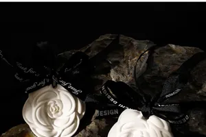 Detail of rose-shaped plaster air freshener with black ribbon on natural rock