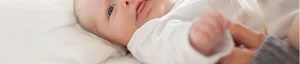 Close-up of soft white cotton baby romper fabric texture in a cozy home setting