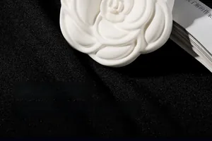 Macro detail of a white camellia shaped gypsum fragrance diffuser stone on black surface