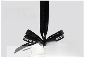 Macro detail of white rose plaster diffuser with branded black ribbon and metal ring