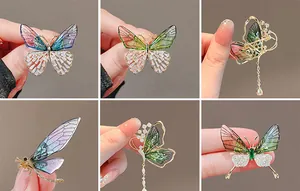 Detailed close-up of emerald butterfly brooches with crystal inlay and gold tassels