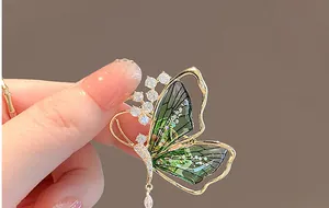 Detailed close-up of emerald green butterfly brooch with zircon inlays and gold trim