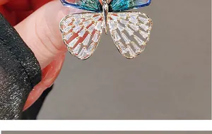 Macro shot of butterfly brooch with emerald gradient wings and gold zircon inlay details