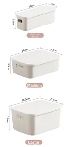 Detailed view of three sizes of matte white plastic storage bins with lids and recessed handles