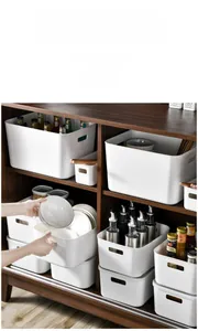 Close-up of white plastic storage bins with handles in a dark wooden cabinet organizer