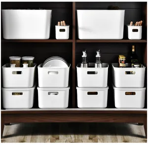 Close-up of white matte plastic storage bins with ergonomic handles in kitchen cabinets