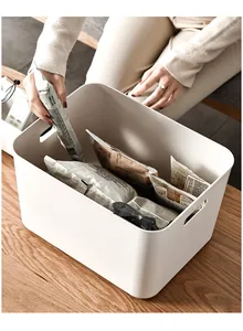White plastic storage bin with handles filled with various snack bags on a wooden desk