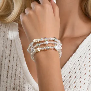 Detail eines dreilagigen Perlenarmbands mit Muschelanhänger, Perlen und bunten Kristallen