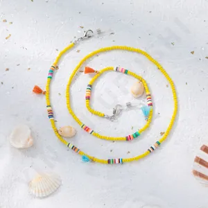 Détail de perles en verre jaunes avec accents colorés en argile et petits coquillages
