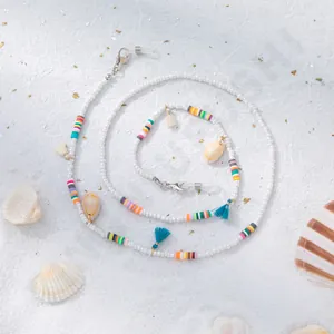 Détail de la chaîne de lunettes perlée avec coquillages et glands sur fond de sable