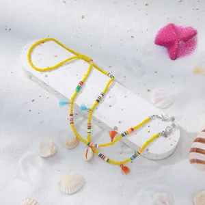 Détail d'une chaîne à lunettes en perles jaunes avec pompons et coquillages naturels