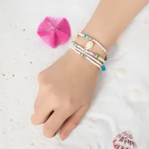 Détail d'un ensemble de bracelets bohèmes en perles avec coquillages et pompons