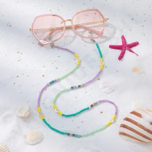 Detailansicht der bunten Brillenlkette mit Herzperlen auf sommerlichem Sandhintergrund
