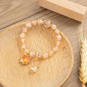 Dettaglio macro di perline di cristallo arancione con ciondolo margherita in oro