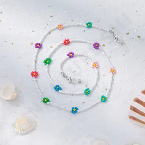 Detail einer bunten Blumen-Perlenkette für Brillen mit silbernem Karabiner auf Sand