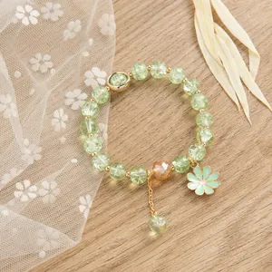 Dettaglio del bracciale in cristallo verde con ciondolo a margherita e accenti dorati