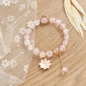 Dettaglio del bracciale con perline di cristallo rosa, ciondolo a margherita e oro