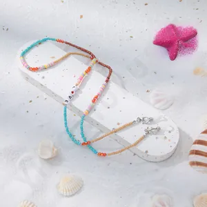 Detail der Brillen-Perlenkette mit LOVE-Buchstabenperlen und Muscheln am Strand
