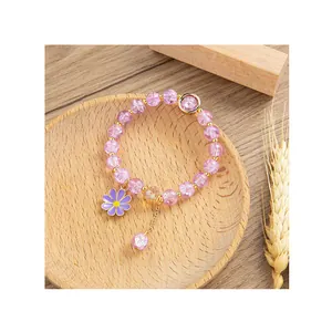 Bracciale di perline con ciondolo a margherita viola su un vassoio di legno