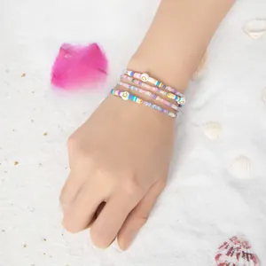 Detail von bunten Polymer-Ton- und Goldherzperlen-Armbändern auf einem Strandhintergrund