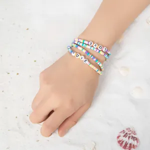 Dreiteiliges buntes Armband-Set aus Tonperlen mit LOVE-Buchstaben auf Strandsand