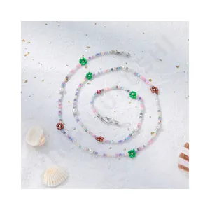 Bunte handgefertigte LOVE-Brillenkette mit Makronen-Perlen und weißen Perlen auf weißem Grund