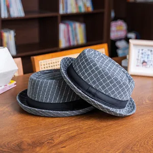 Detail of dark grey plaid and pinstripe pork pie hats on a warm wooden background
